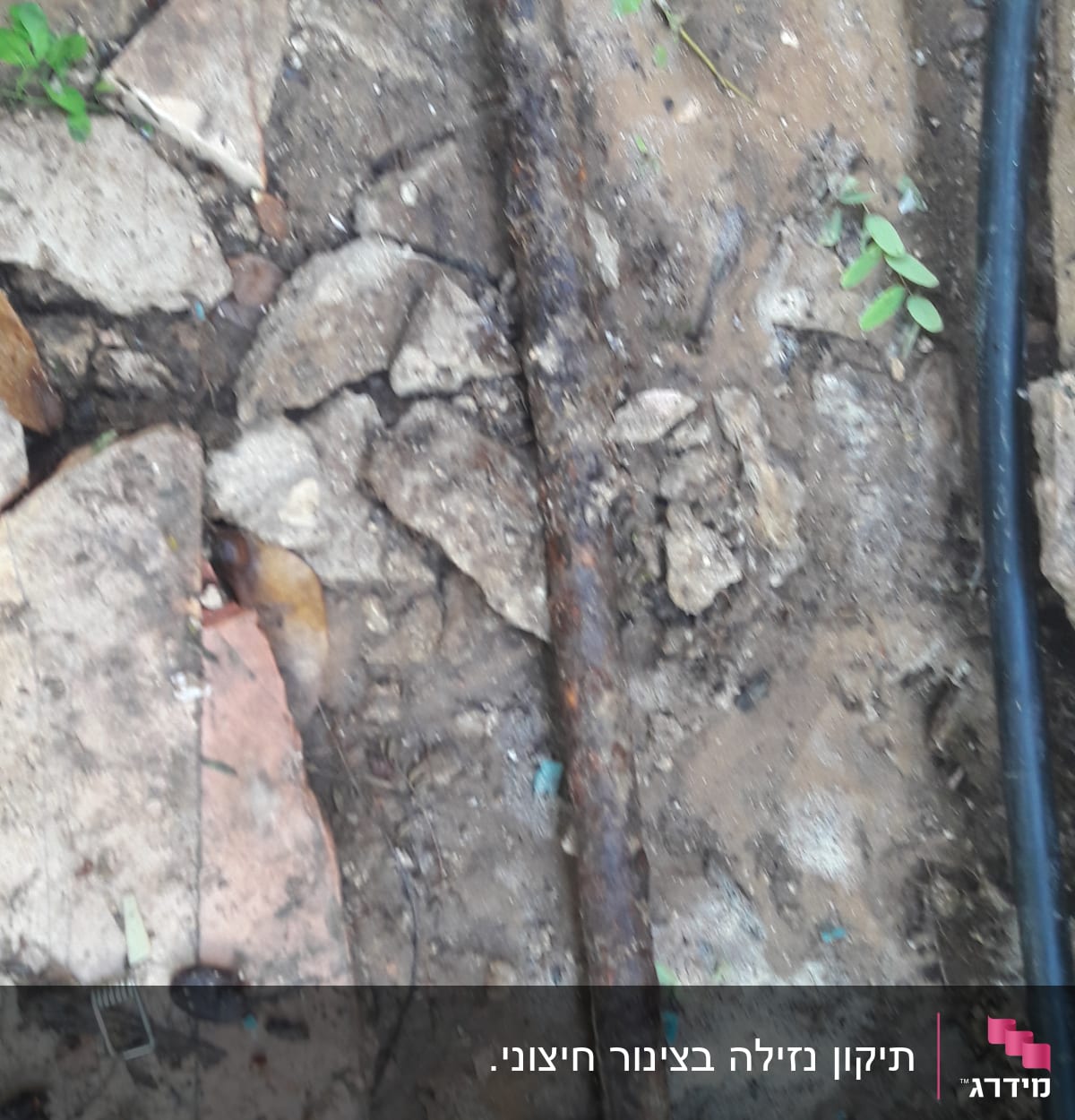 צינור חלוד באדמה עם אבנים מסביב